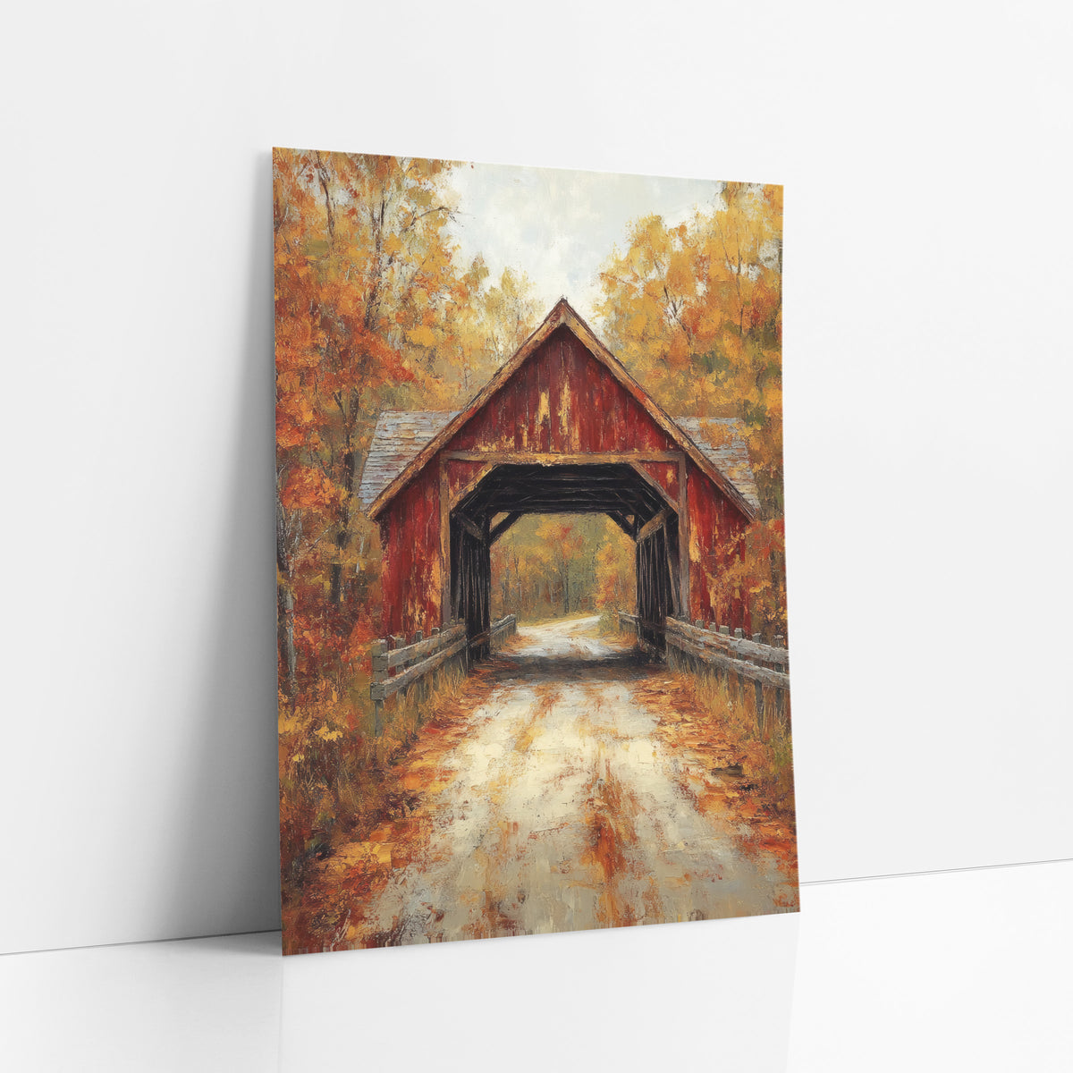 Rust Red Bridge Birch Lane Painterly art print leaning against a white wall – weathered red covered bridge on a leaf-strewn