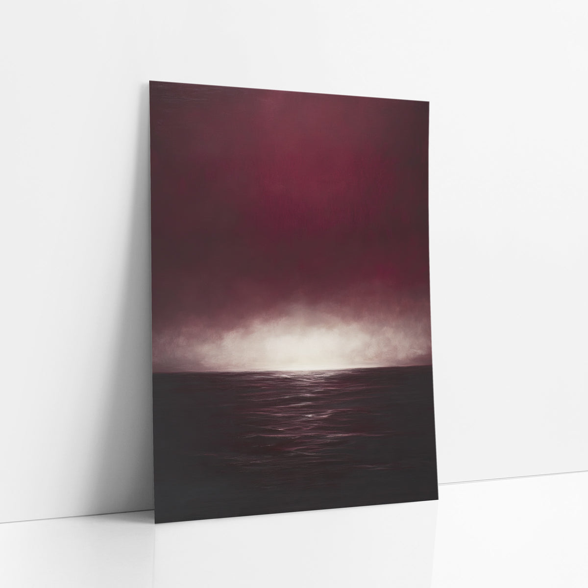 Ruby Sea Glow Moody Seascape art print leaning against a white wall – deep burgundy sky with a glowing pale horizon above