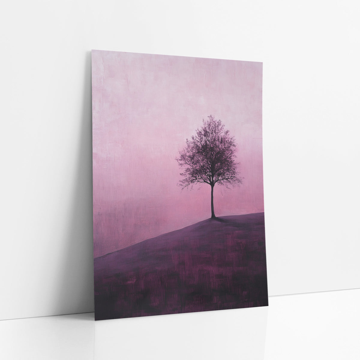 Lone Tree on Plum Hillside art print leaning against a white wall – lone leafy tree on a plum-colored hillside against a pink