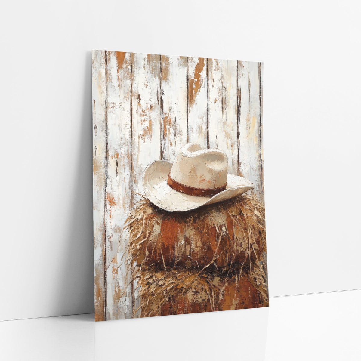 Cowboy Hat on Hay Western art print leaning against a white wall – cream cowboy hat with a rust-brown band on a stack