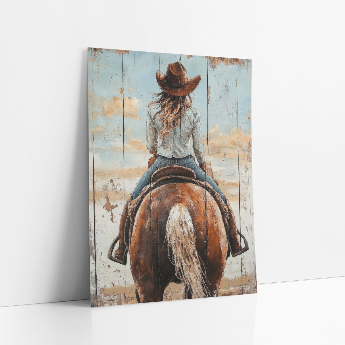 Cowgirl Wind-Blown Hair Sky Rustic art print leaning against a white wall – cowgirl in a brown hat seen from behind riding