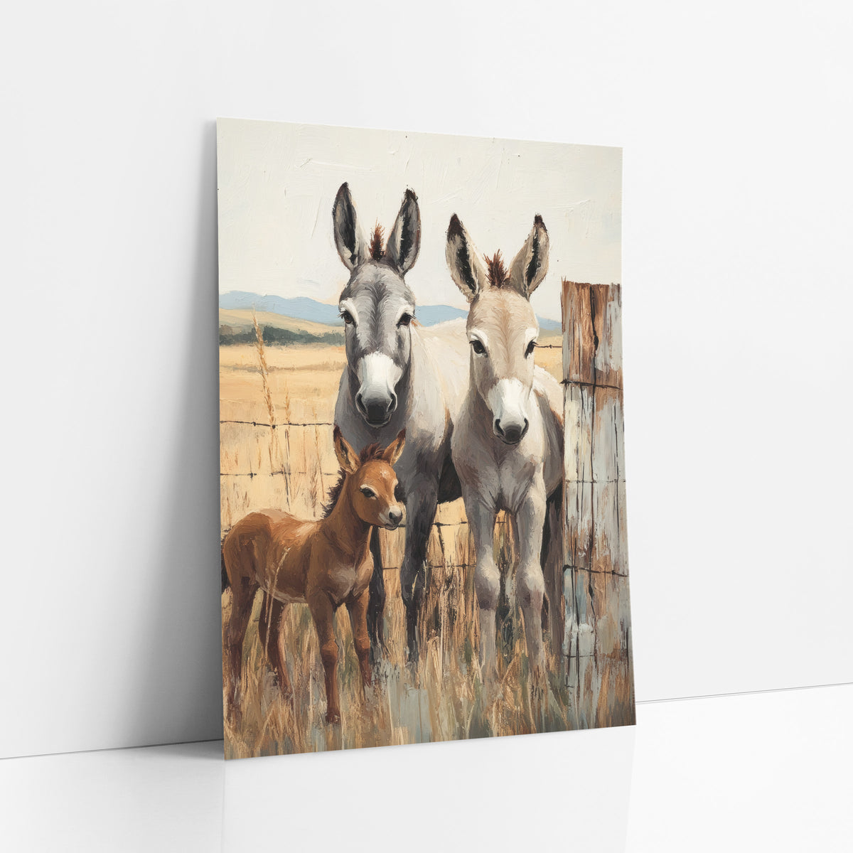 Donkey Family Ranch Western art print leaning against a white wall – gray donkey, pale tan donkey and reddish-brown foal