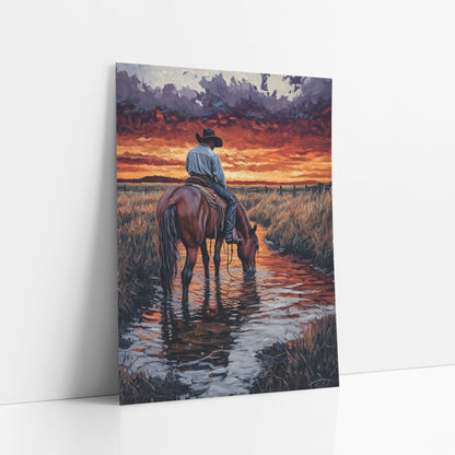 Cowboy Horse Creek Sunset Western art print leaning against a white wall – cowboy in black hat on a bay horse drinking