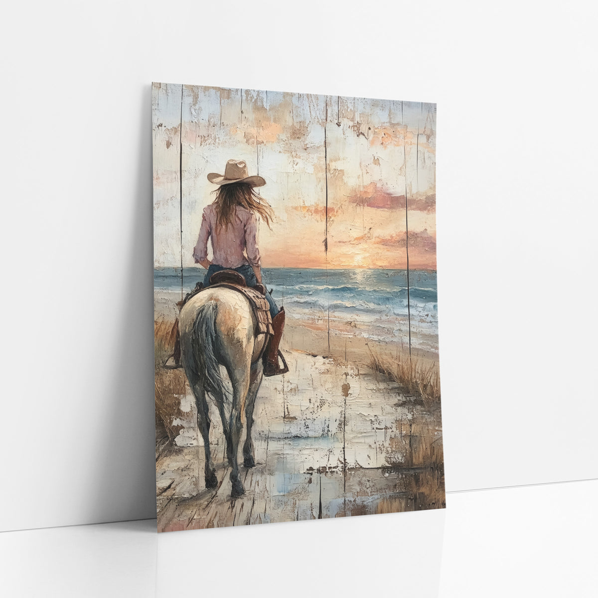 Cowgirl Riding Seaside Sunset Western art print leaning against a white wall – cowgirl in a hat riding a pale horse