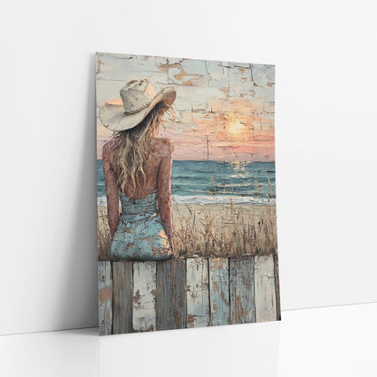 Cowgirl Watching Seaside Sunset Western art print leaning against a white wall – woman in a cream cowboy hat and blue dress