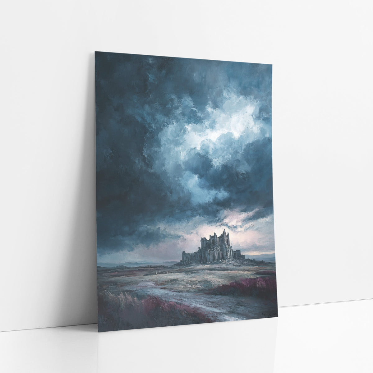 Distant Abbey Heath Moody art print leaning against a white wall – ruined gothic abbey on a moor under dark storm clouds