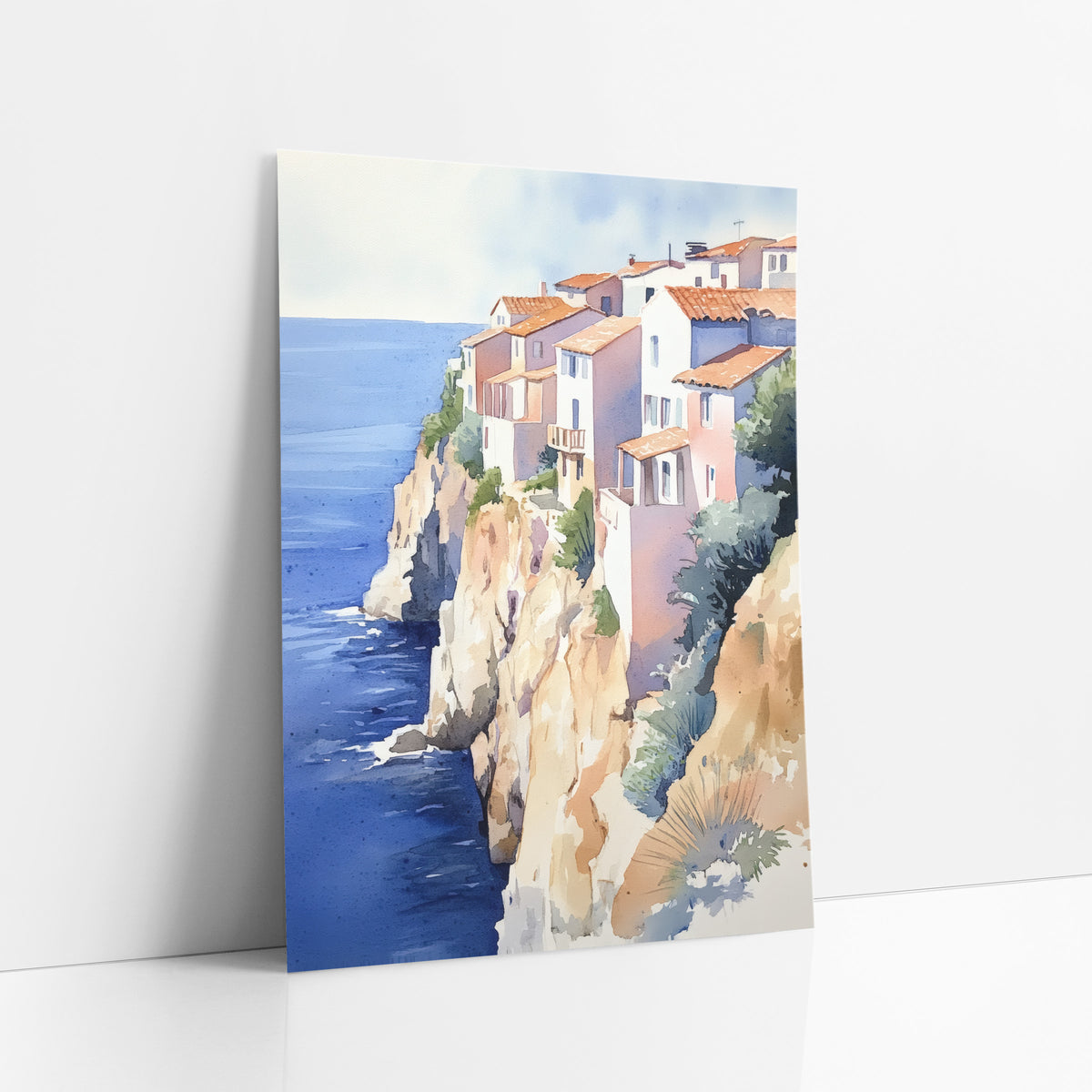 Terracotta Roofs Overlook Seaside Boho art print leaning against a white wall – watercolor of white and pink houses