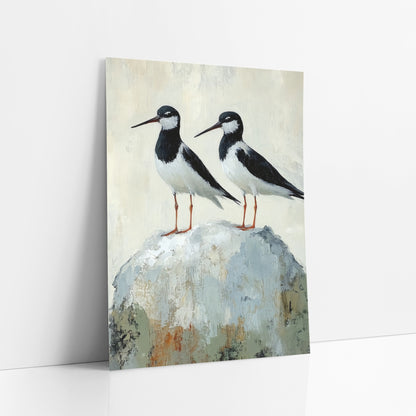 Twin Stilts Gray Boulder Coastal art print leaning against a white wall – two black and white shorebirds with long bills